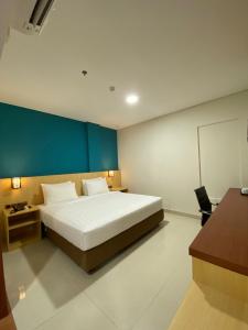 a bedroom with a large bed and a blue wall at Erbe Style Jayapura Papua By Horison in Jayapura