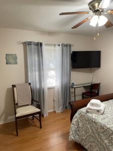 1 dormitorio con 1 cama, 1 silla y TV en Sanford Lake Mary Quiet Rooms, en Sanford