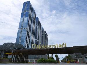 a tall building with a sign in front of it at Meisterstadt Pollux Habibie in Batam Center