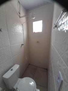 a small bathroom with a toilet and a window at Pousada do Forte in Praia Grande