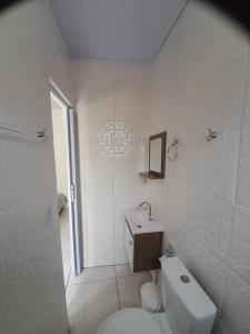 a white bathroom with a toilet and a sink at Pousada do Forte in Praia Grande