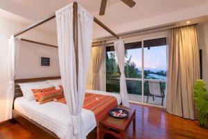 ein Schlafzimmer mit Himmelbett und großem Fenster in der Unterkunft Katamanda villa Moon 3 Bed seaview near Kata Beach in Kata Beach + 30 Fotos