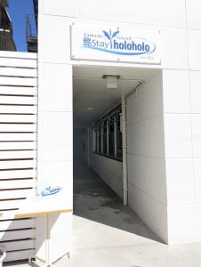 a walkway leading into a building with a sign on it at Shima Stay holoholo in Zamami