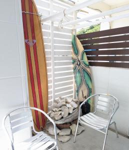 a couple of chairs and a surfboard on a porch at Shima Stay holoholo in Zamami