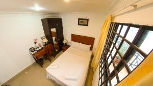a small room with a white bed and a window at Riverside Hotel Phnom Penh in Phnom Penh