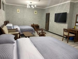 Cinzano Complex في سمرقند: غرفة فندقية بثلاث اسرة وتلفزيون بشاشة مسطحة