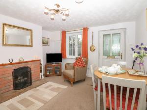 Poppy Cottage في Charlton Marshall: غرفة معيشة مع موقد وطاولة