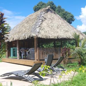 a group of lounge chairs in front of a hut at Vai Iti Lodge in Afaahiti