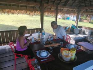 Ein Mann und eine Frau sitzen an einem Tisch mit Essen in der Unterkunft Vai Iti Lodge in Afaahiti