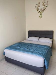 Bett mit blauer und weißer Decke in einem Zimmer in der Unterkunft D'Rusa Homestay in Port Dickson