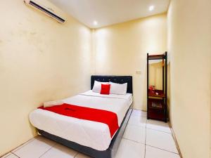 a bedroom with a bed with a red blanket at RedDoorz near Alun Alun Sidoarjo in Sidoarjo