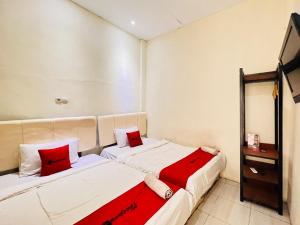 two beds in a small room with red pillows at RedDoorz near Alun Alun Sidoarjo in Sidoarjo +3 photos