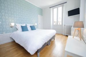 a bedroom with a large white bed with blue walls at Villa Clément Sens Appart'Hotel in Sens