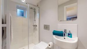 La salle de bains blanche est pourvue d'un lavabo et d'une douche. dans l'établissement Wimbledon Studios, à Londres