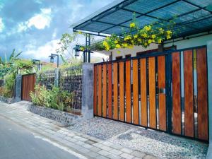 a fence with a wooden gate with yellow flowers on it at InN House Homestay in Dadapan
