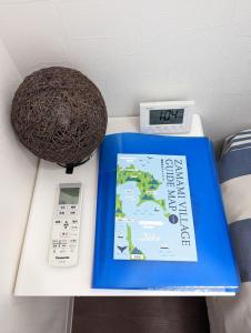 a clock and a book on a table with a thermometer at Shima Stay holoholo in Zamami