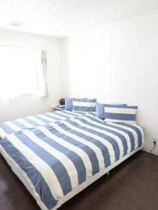 a blue and white striped bed in a white room at Shima Stay holoholo in Zamami