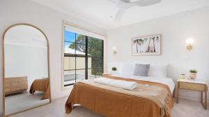 a bedroom with a bed and a large window at Palm Breeze in Kiama