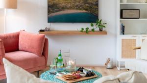 a living room with a table with food and a pink chair at Palm Breeze in Kiama