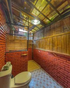 a bathroom with a toilet and a red brick wall at Sa Sa Lao in Luang Prabang