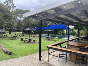 un grupo de mesas de picnic y sombrillas en un parque en Tyalgum Hotel, en Tyalgum