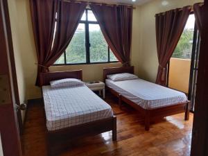 two beds in a room with a window at Tagaytay Rest House in Tagaytay