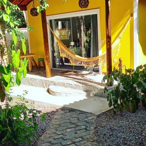 a yellow house with a hammock in front of it at Chalé Jacu Beach in Pipa