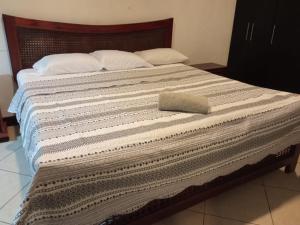 a bed with a blanket and a pillow on it at Departamento con piscina frente al mar en Manta in Manta