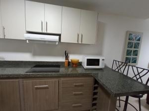 a kitchen with white cabinets and a counter with a microwave at Departamento con piscina frente al mar en Manta in Manta