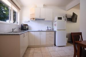 a kitchen with white cabinets and a white refrigerator at Adina Lodge Holiday Apartments in Bright