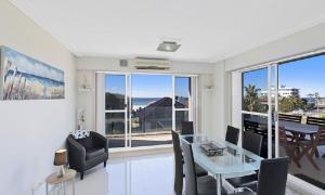 a dining room with a glass table and chairs at Sandy Cove Apartment The Entrance 12 in The Entrance