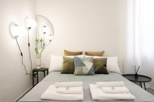 a white bedroom with a bed with two towels on it at Room 47 Temporary Home in Tivoli