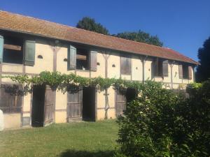an old building with wooden doors and a yard at Bel appartement et jardin chez Maison Devaux in Rion-des-Landes