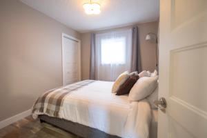 una camera da letto con un letto con lenzuola bianche e una finestra di Le Court-Toit a Rouyn-Noranda