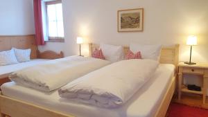 a bedroom with two beds with white sheets and pillows at Ferienwohnungen Budererhof in Bad Wiessee +90 photos