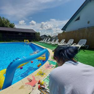 a woman standing next to a swimming pool at Satul de Vacanta Campo Euro Club in Partizanii