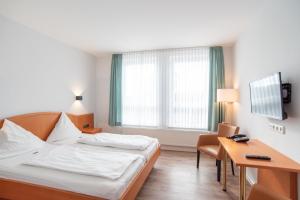a hotel room with a bed and a desk at Butjadinger Hof in Burhave