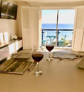 two glasses of wine on a counter with a view of the ocean at Stylish Sea View Apartment with Parking in Penzance