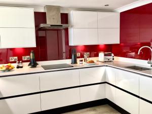 a kitchen with white cabinets and red walls at Stylish Sea View Apartment with Parking in Penzance