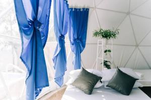 Habitación con cortinas azules y cama con almohadas. en Family Getaway Dome Glamping w/ Private Hotspring en Lubo