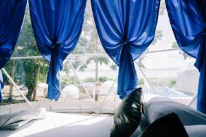 a window with blue curtains in a bedroom at Family Getaway Dome Glamping w/ Private Hotspring in Lubo