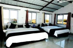 three beds in a room with windows at The Forest View Resort in Khilchipur