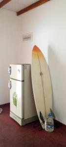uma prancha de surf encostada a um frigorífico num quarto em Surf Forever em Midigama East