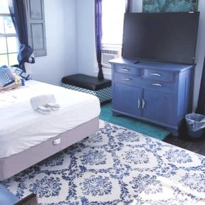 Room in Apartment - Blue Room in Delaware في دوفر: غرفة نوم مع سرير وتلفزيون في خزانة
