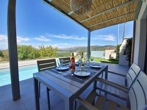 a table and chairs on a patio with a view of a pool at ONAR - LUXURY VILLAS in Argostoli