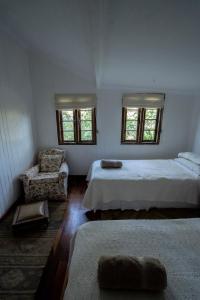 a bedroom with two beds and a chair and two windows at The 100 Year Old House in Nanyuki