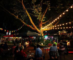 a group of people sitting at tables under a tree with lights at Hotel de Plataan Delft Centrum in Delft