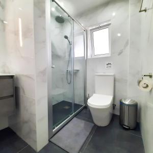 uma casa de banho com um WC e uma cabina de duche em vidro. em Sea Breeze Central, 2bed em Limassol