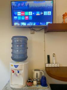 TV en la pared con un contenedor de agua encima de una nevera en Kost Studio 62 en Depok