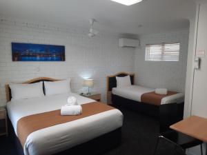 a hotel room with two beds and a desk and a table at Cleveland Motor Inn in Cleveland